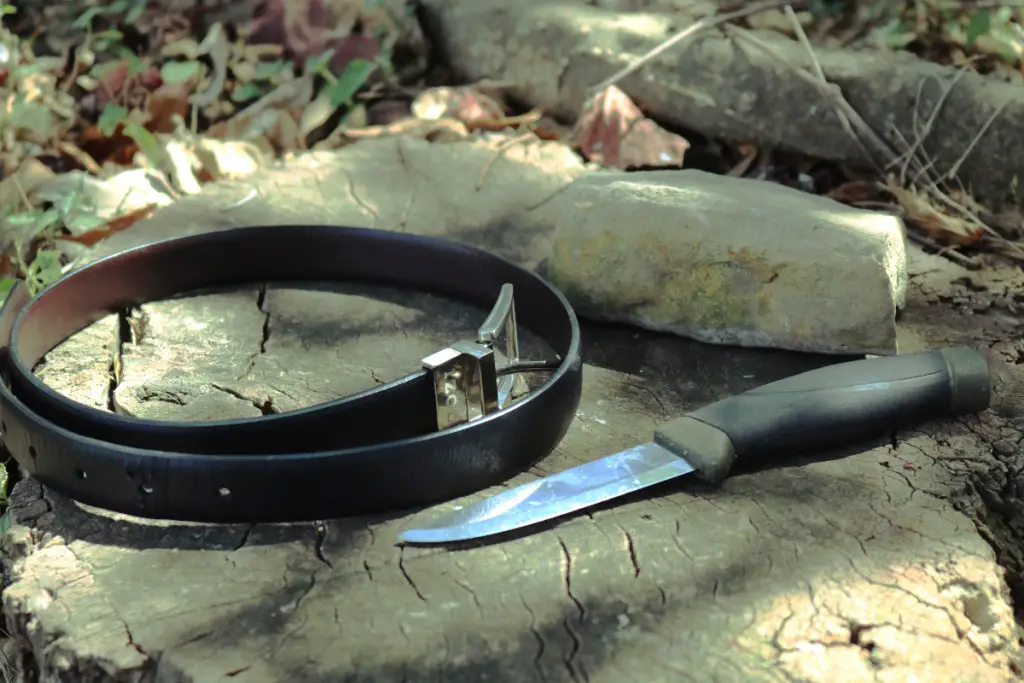 dull knife with a belt and stone on a stump