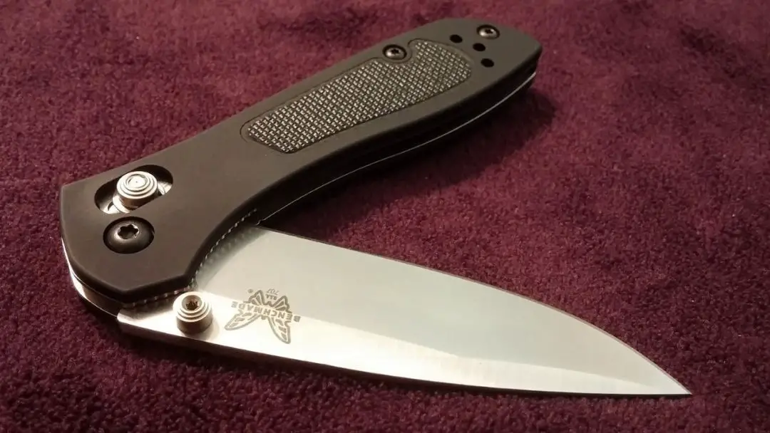 photo of a brown benchmade knife half open laying on ugly purple carpet