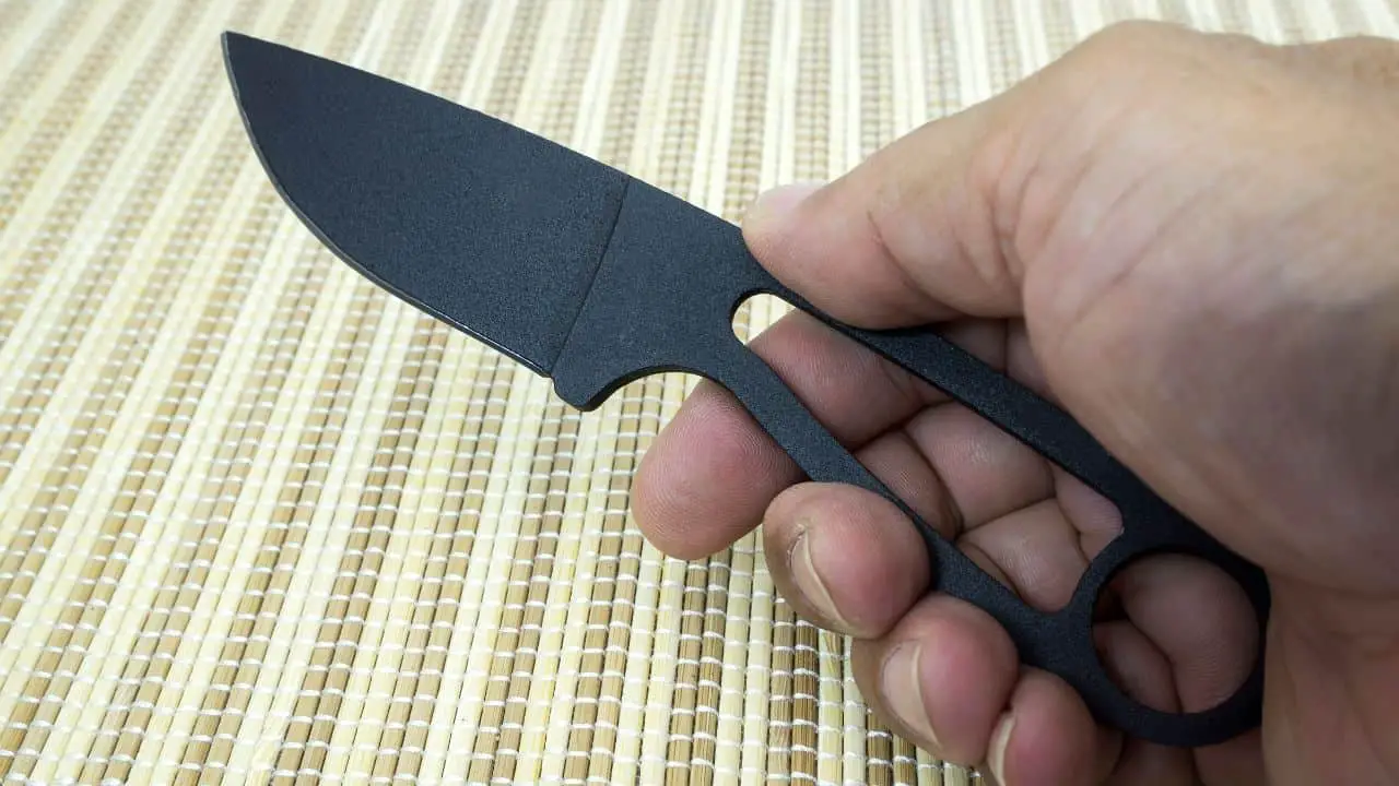 photo of a black fixed blade knife with massive hole in the handle for paracord