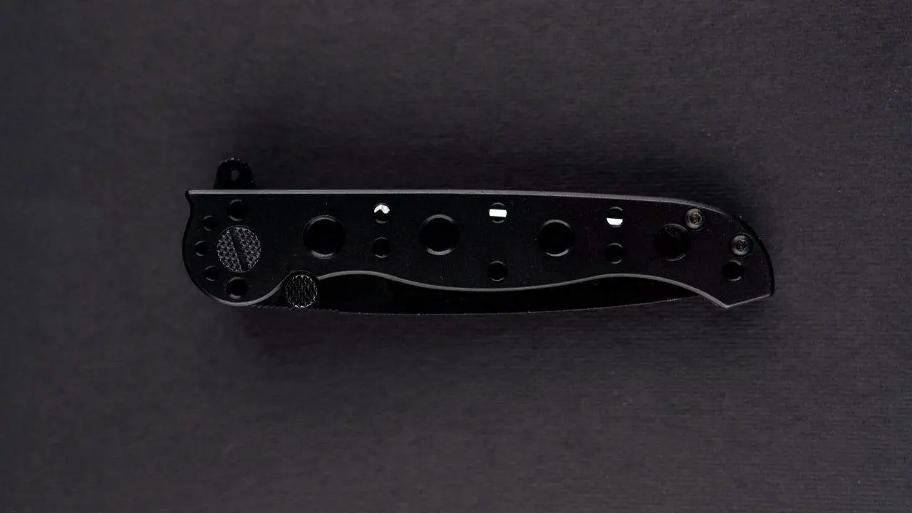 photo of a dark colored folding knife closed on a black background