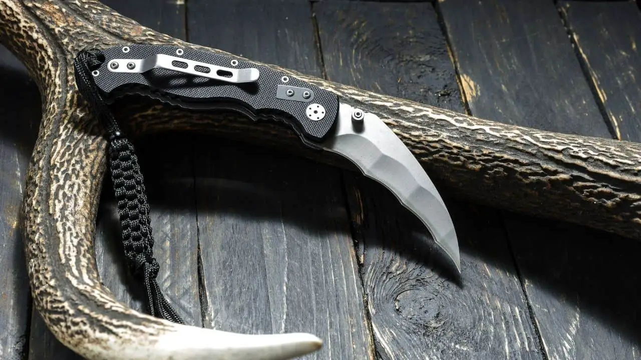 photo of a folding karambit knife leaning up against an antler