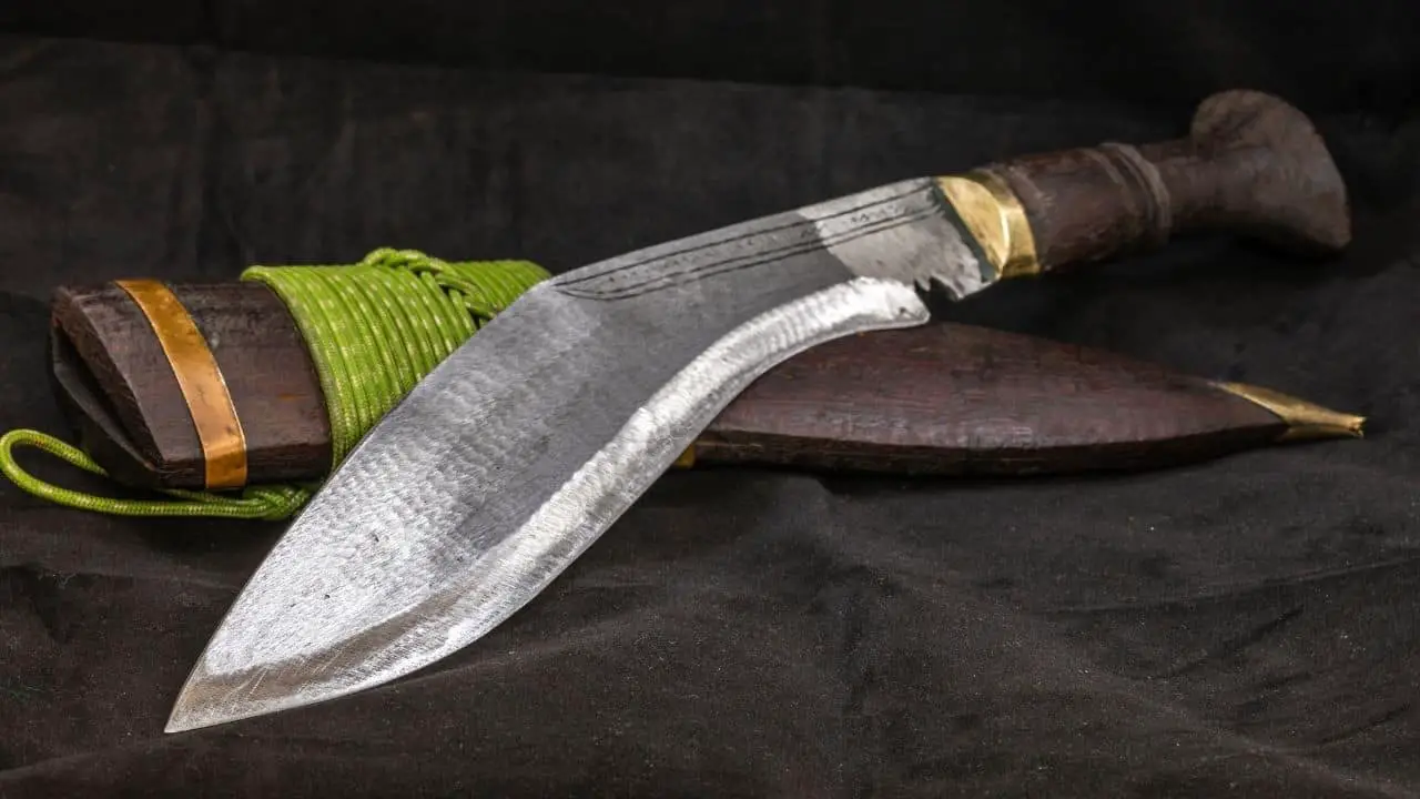 photo of a kukri knife and its sheath laying on a black cloth background