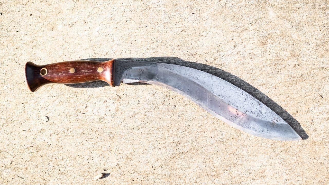photo of a traditional kukri knife with a wooden handle laying on the ground