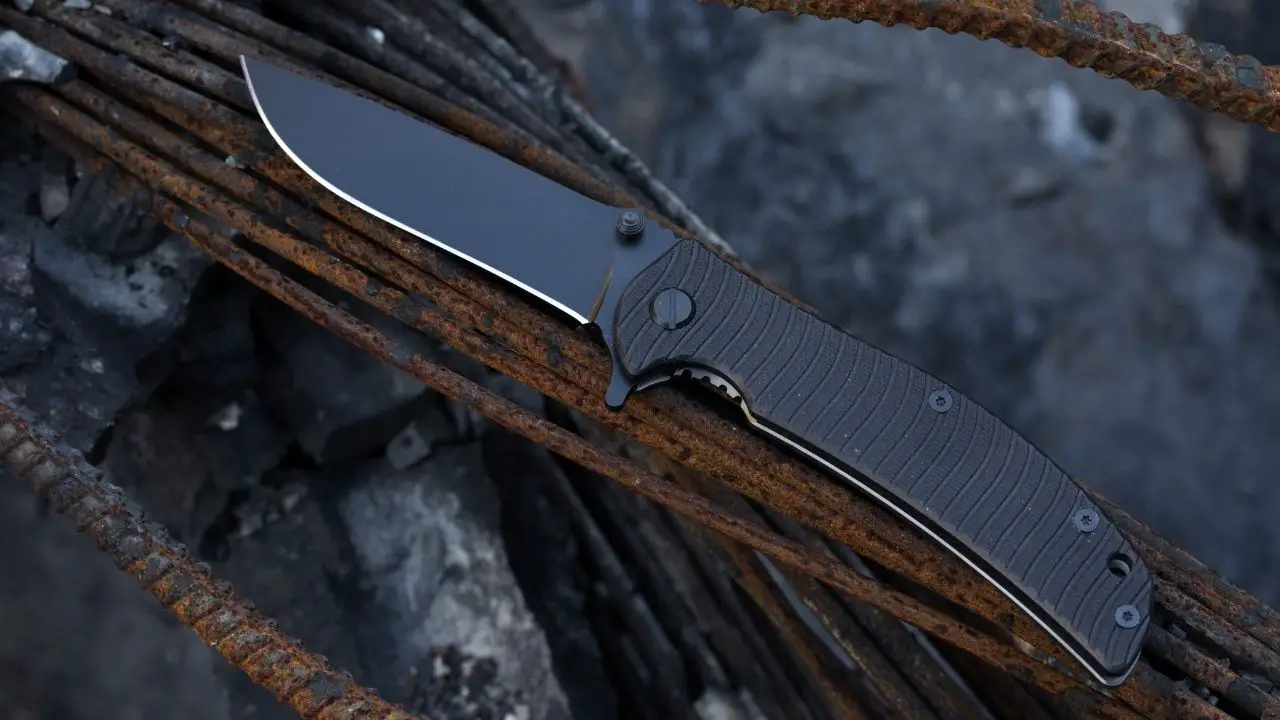 photo of a dark colored pocket knife on rusted metal