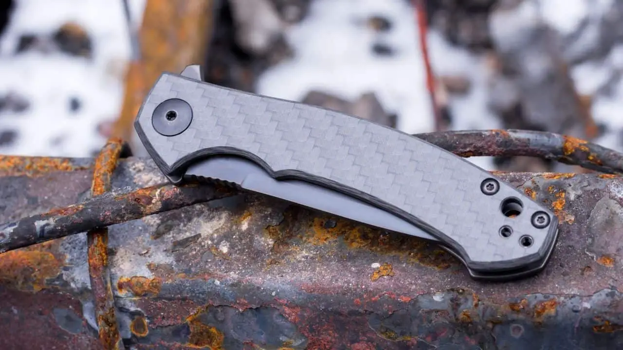 photo of a titanium folding knife closed on a rusty piece of metal