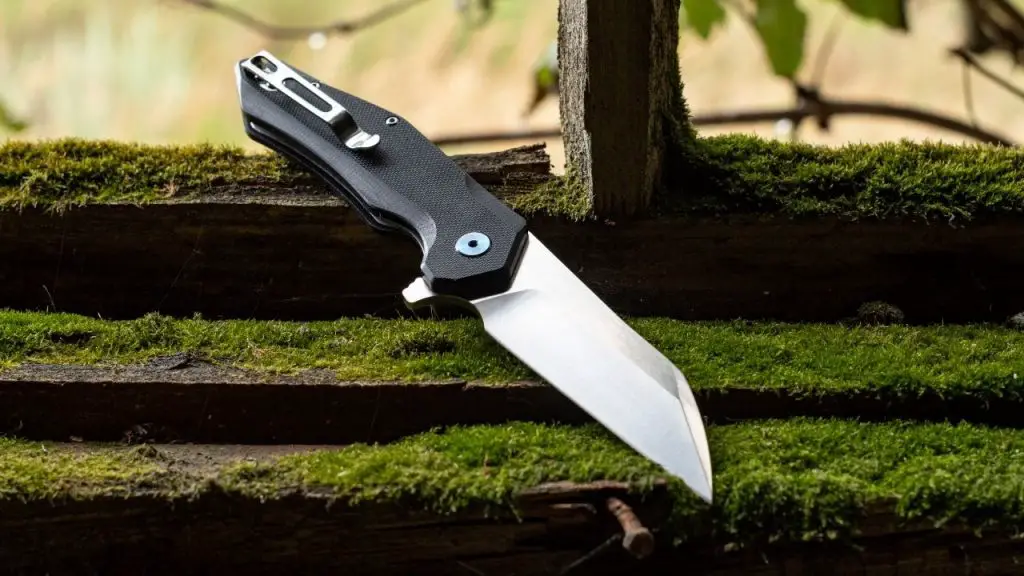 photo of a folding knife with wharncliffe style blade on mossy wood