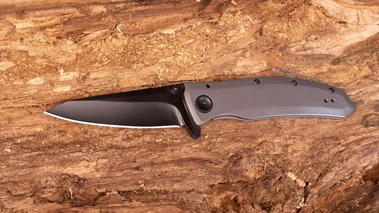 photo of a knife with gray handle and black blade on wooden surface